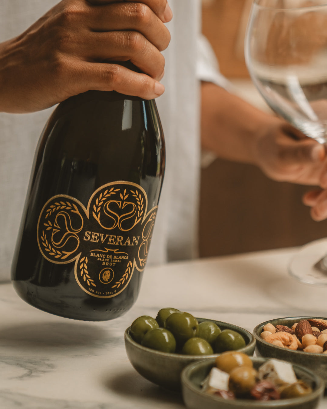 A bottle of Severan Black Label Blanc de Blancs Brut held over a marble table