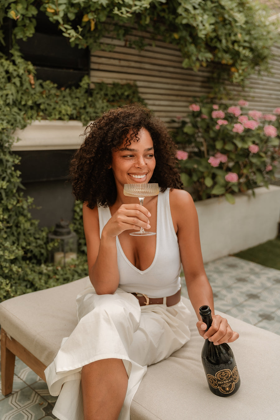 A woman in a garden raising a glass of Severan Black Label, laughing